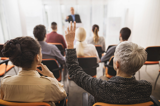 Woman raising her hand to ask a question during a meeting
