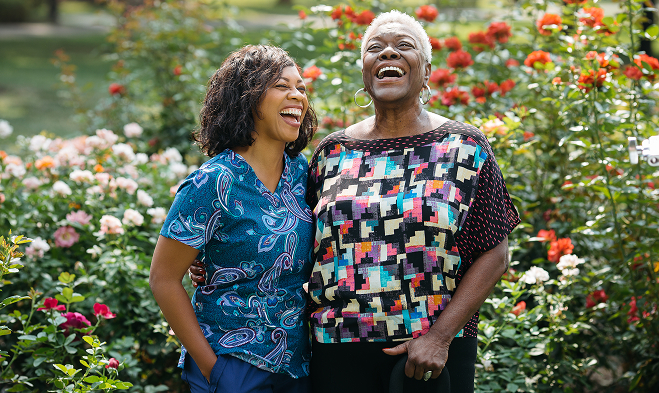 Caregiver laughing with elderly woman while on a outside walk